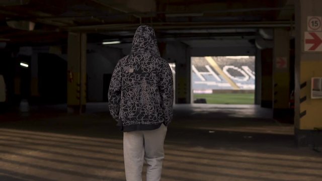 Young hooligan streetstyle guy going on the football stadium at the evening at autumn