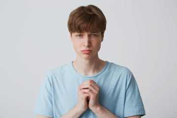 A young guy is standing with a pleaded expression on his face, his puffed-up lower lip, his hands...