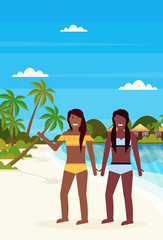 couple bikini women on tropical island with villa bungalow hotel on beach seaside green palms landscape summer vacation concept flat vertical