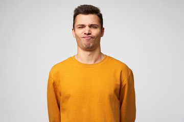 Studio shot of a young guy standing confident, chin up, on the face expression of a success, winning, show class, winner, pleased enjoying himself, isolated over white background