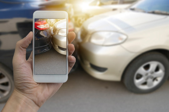 Close up hand holding smartphone and take photo at The scene of a car crash