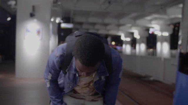 Black skin African  guy is late and runs after a departing tram on the platform in the night