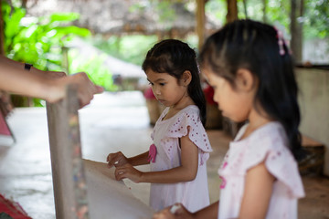 Fototapeta premium Two cute asian child girls learning how to make recycling paper from poop of elephants together