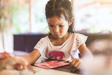 Cute asian child girl make a craft with recycling paper from poop of elephants in learning center