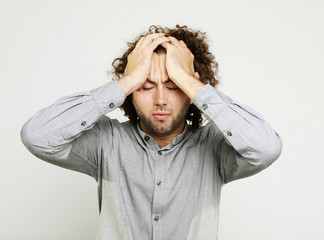 Close up of frustrated young man with head in hand against white background