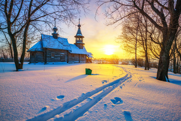 Small russian church in winter park at sunset