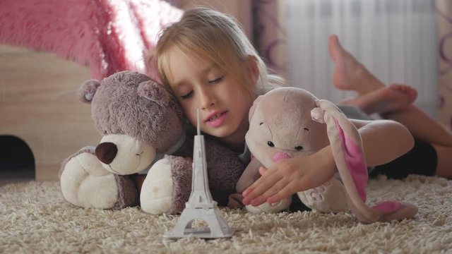 Little girl with her toys at children room dreaming about travel to Paris. Child dream, vacation and travel concept.