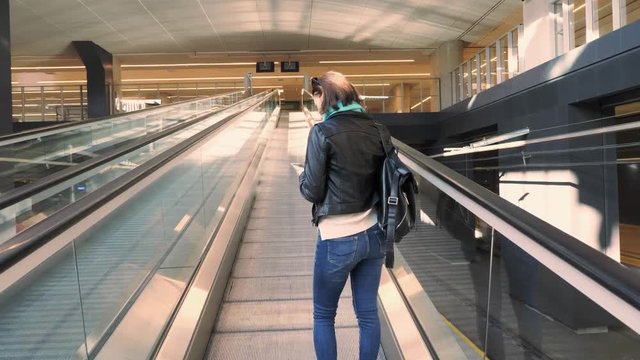 Automatic escalator without steps at modern railway station. Moving straight tape going up with woman or girl on it, on background of modern interior of large glass building, stock video