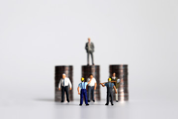 The pile of coins and miniature people. A concept on labor disputes.