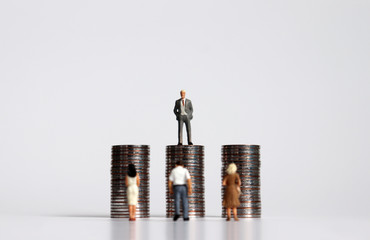 Miniature people with piles of coins. The concept of wage bargaining between employers and workers.