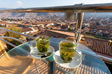 Enjoying cups of coca tea with view of Cusco city in Peru