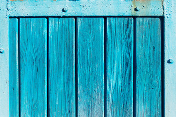 Aqua colored wooden gate with iron stripes