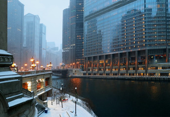 Beautiful winter night in Chicago. Chicago downtown cityscape and Riverwalk. Twilight winter view during snowfall. Illinois, Midwest USA. Urban architecture and big city life background.