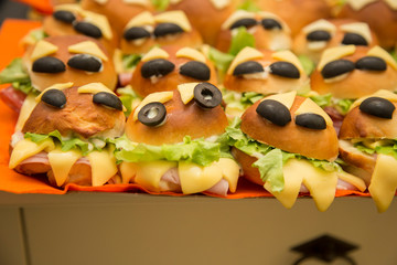 horizontal image with detail of many round sandwiches stuffed and decorated for halloween party