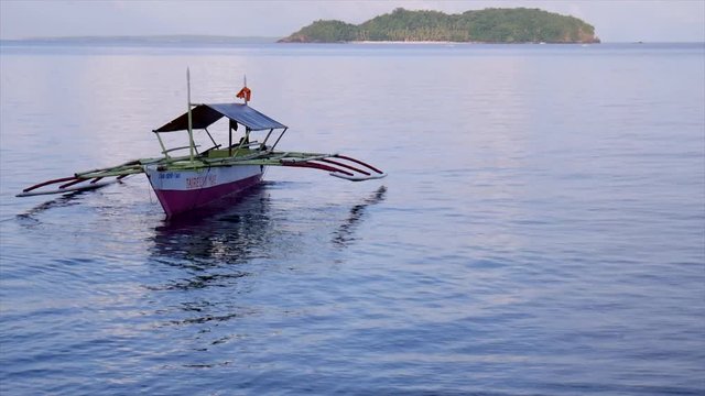 Outrigger boat at dusk off of Biliran Island, Philippines, with Dalutan Island in the background.