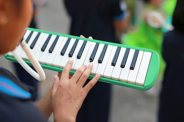 Close up hands of students playing melodian marching band the music you learned in high school.
