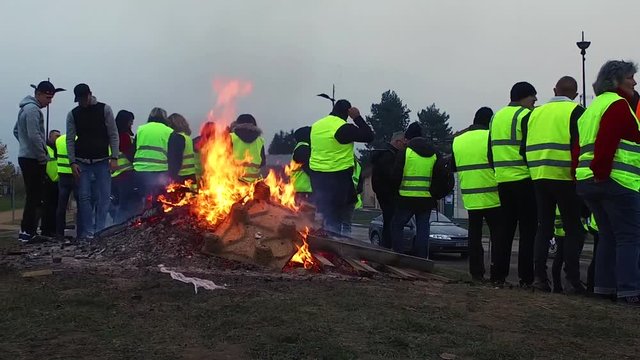Protesters in France. Members of the "yellow vests" movement  (gilets jaunes) have lit a fire at a crossroad, and are blocking the roads to protest against the oil prices and Macron's policy.