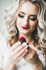 Beautiful bride wearing fashion wedding dress with feathers with luxury delight make-up and hairstyle, studio indoor photo shoot