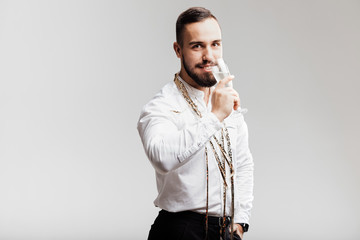 Handsome man smiles and holds glass of champagne on a white background. Party time