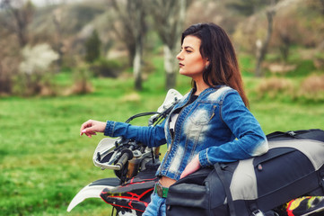Fototapeta na wymiar A young girl mototourist in nature . Motorcycle travel concept