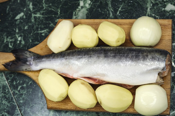 the fresh raw pink salmon potatoes and onions on cutting Board