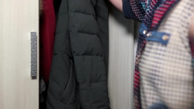 Woman opening sliding door of wardrobe and getting winter jacket from it. Close up view