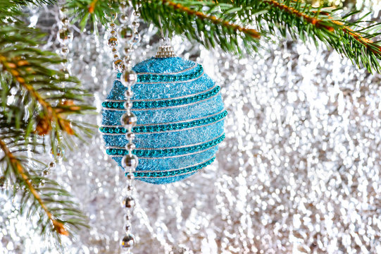 Big beautiful blue ball, green branch of spruce on a light blurred background. Festive greeting card. New Year, Christmas background. Free space for the project