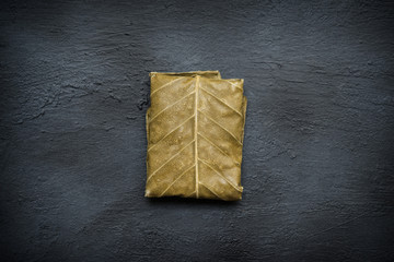 Raw tempeh wrapped in leaf, top down view.