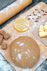 Cookie dough on the kitchen table. Ingredients - butter, lemon, flour, sugar, cloves.