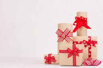 Festive gift boxes of kraft paper with red ribbons on white wood board. Template for your advertising and design.