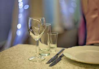 Wine glasses, two table knives and a plate on the table in the restaurant with a beautiful blurred background and bokeh