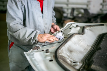 Car repair in car service. Locksmith grinds car detail, hands close-up