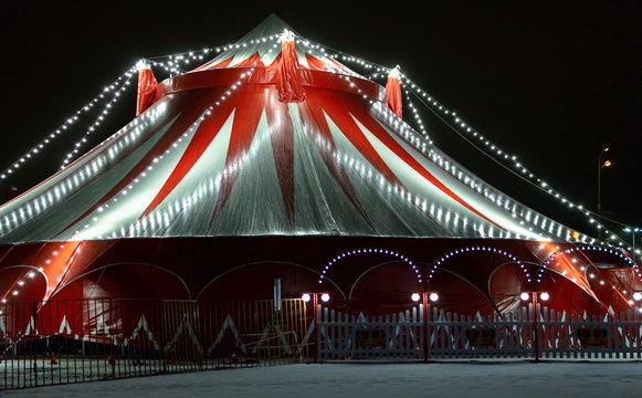 The circus illuminated and decorated with garlands of light bulbs, at night