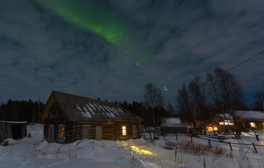 Aurora over the winter forest and a small wooden house, Yamal
