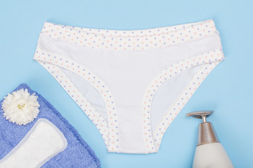 Beautiful women's panties with a sanitary napkin and towel on blue background