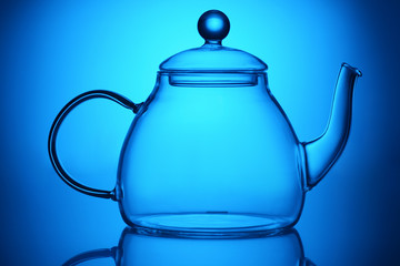 Transparent glass teapot on blue