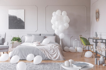 Fototapeta na wymiar Real photo of a simple bedroom interior decorated with balloons, birthday cake and painting