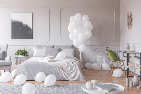 Real photo of a simple bedroom interior decorated with balloons, birthday cake and painting