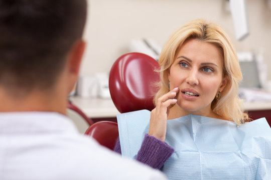 Gorgeous Mature Woman Talking To Her Dentist Before Receiving Medical Treatment For Her Toothache. Beautiful Female Patient Having Teeth Problems, Visiting Dentist. Curing, Oral Care Concept