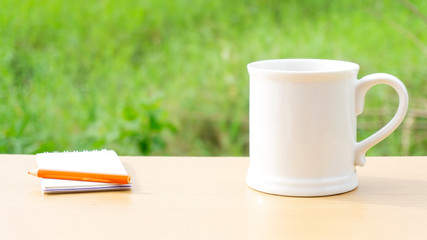 Hot coffee in the morning write new ideas Props decorations a pencil on wooden table nature .Beautiful landscape Green field background, Copy Space..