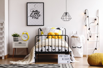 Yellow knit pillow on single metal bed in bright bedroom interior with white scandinavian ladder,...