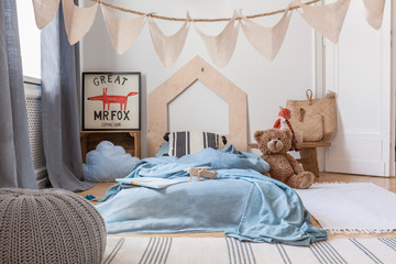 Blue sheets on bed and grey pouf in kid's bedroom interior with poster and plush toy. Real photo © Photographee.eu