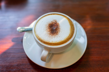 Cappuccino hot coffee romantic sunshine on wood background.