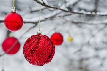 Red Christmas tree footwear toys in the form of balls hanging on the branches of a tree close up