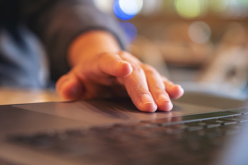 Closeup image of hands using and touching on laptop touchpad on wooden table