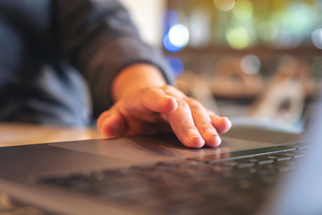 Closeup image of hands using and touching on laptop touchpad on wooden table