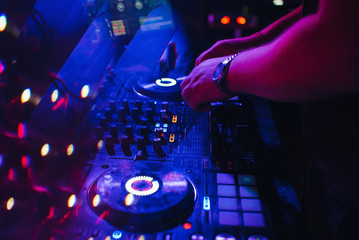 Fototapeta na wymiar DJ plays with his hands on a music mixer in a nightclub