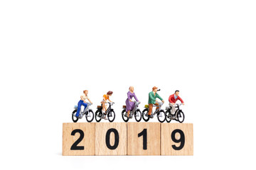 Miniature people : Friend Group ride bicycle with wooden number  2019 , Happy New Year  concept.