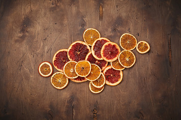 Heap of dried orange and grapefruit rings on dark brown vintage rustic wooden background