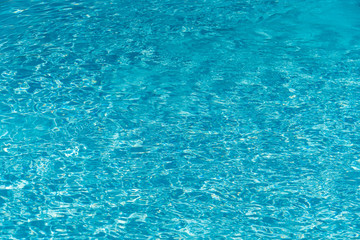 Blue water in swimming pool background. Ripple Water in swimming pool with sun reflection. Blue swimming pool rippled water detail